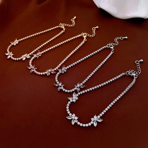 Detail view of gold and silver zircon flower tennis bracelets on brown satin fabric