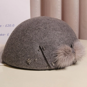 Detail of dark gray wool felt hat with light brown fur ball and sparkling rhinestones