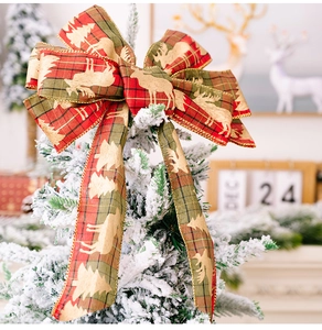 Detail of red and green plaid Christmas bow with golden reindeer patterns on a tree