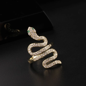 Macro shot of gold snake ring with white cubic zirconia pavé and green gem eyes