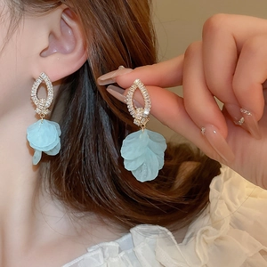 Close-up of light blue flower earring with shimmering zircon knots on a model's ear