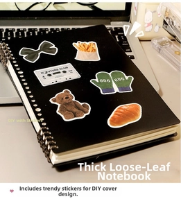 Detail of black DIY loose-leaf notebook with dual metal coils and cartoon bear stickers