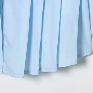 Detail of light blue pleated hem on a long sleeve shirt with clean stitching and woven texture