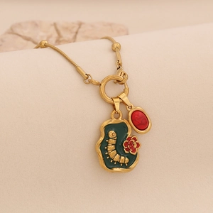 Detail of vintage gold necklace with green enamel pendant and caterpillar motif