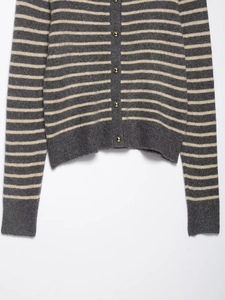 Detail of grey striped knit cardigan featuring golden metal buttons and soft texture