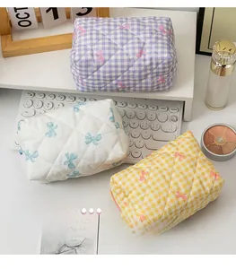 Detailed view of quilted plaid makeup bags with bow patterns in purple, white, and yellow