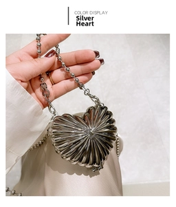 Detail of a silver heart-shaped mini shell bag with textured finish and ball chain handle
