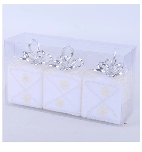 Detailed view of three white flocked Christmas gift box ornaments in a clear package