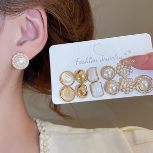 Close-up of 6 pairs pearl and gold stud earrings set on a display card and model ear