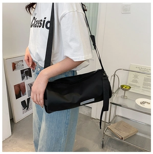 Mannequin portant un sac bandoulière cylindrique noir en nylon avec large sangle en tissu
