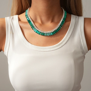 Dettaglio di una collana di lusso con cristallo verde smeraldo indossata da modella