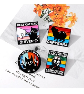 Detailed close-up of cartoon enamel pins featuring cat and capybara designs on cards