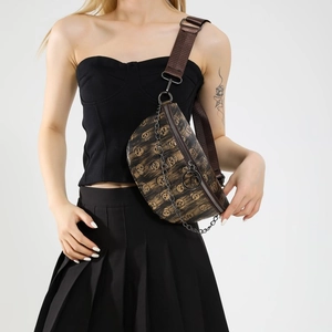 Brown skull pattern fanny pack with chain detail worn by a model in studio setting