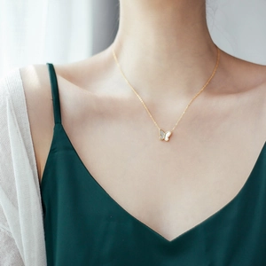 Gros plan d'un collier en acier titane doré avec un pendentif papillon blanc nacré