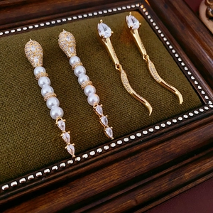 Detail of luxury snake-shaped earrings with gold zircon and elegant pearl accents