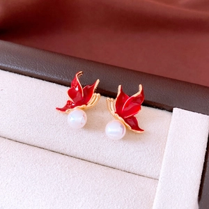 Gros plan de boucles d'oreilles papillon en émail rouge avec placage d'or et perles