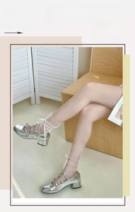 Detail of silver Mary Jane block heels paired with delicate mesh bow socks
