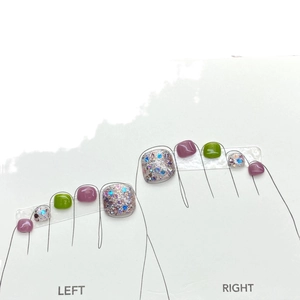 Sparkling purple and green glitter press-on toe nails on a white sizing display card