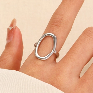 Detailed view of an oval hollow ring in polished silver finish worn on a hand