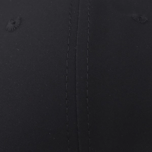 Macro detail of black fabric showing twill texture, double stitching and embroidered eyelet
