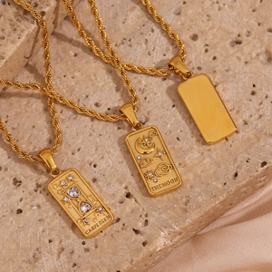 Detailed macro view of 18K gold tarot moon and hourglass pendants on twist rope chains