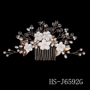Detailed macro view of white ceramic flowers and pearls on a gold bridal hair comb