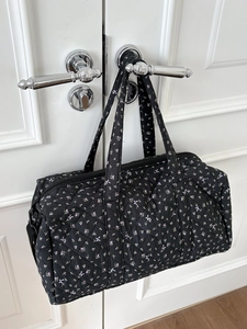 Borsa da viaggio trapuntata a fiori con fiocchi appesa alla maniglia della porta