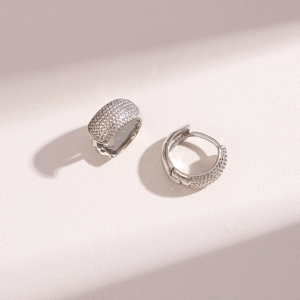 Polished silver hoop earrings encrusted with sparkling cubic zirconia on a soft pink surface