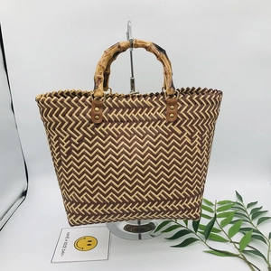 Detail of woven straw tote bag with natural bamboo handle and brown leather accents