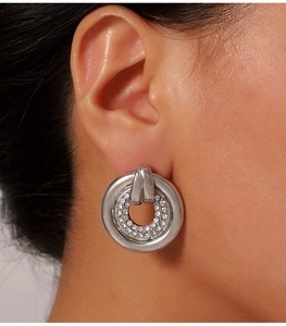 Close-up of a silver hollow hoop earring with crystal inlay worn by a female model