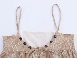 Close-up of brown tank top with white leaf print, pleats and decorative wooden beads