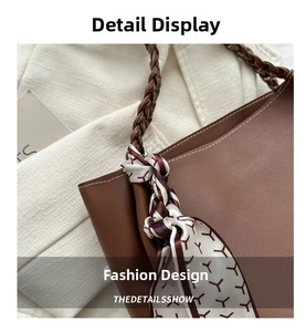 Detail of a brown leather tote bag with woven handles and a geometric pattern silk scarf