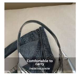 Detailed close-up of the silver metallic handle and smooth glossy texture on the tote bag