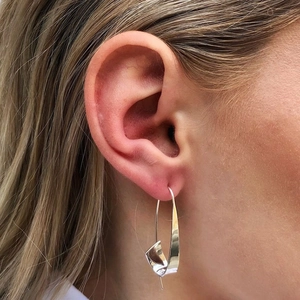 Polished silver gypsy spiral hoop earrings with geometric twist design on model