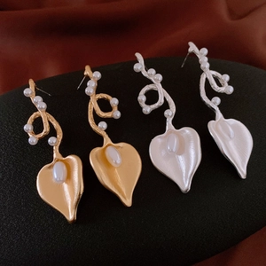 Detailed view of vintage-style heart pearl earrings in gold and silver finish on velvet