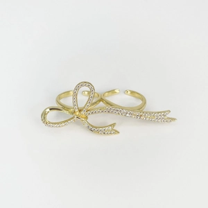 Detailed macro view of a gold-plated double-finger ring with a sparkling crystal bow design