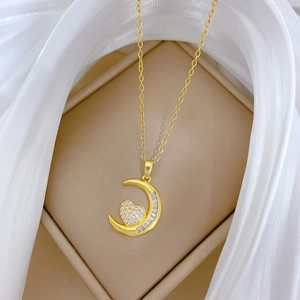 Dettaglio della collana dorata con ciondolo a luna e cuore con cristalli in una scatola