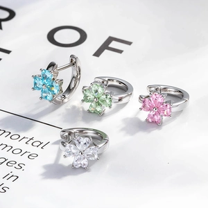 Four-leaf clover earrings with colorful zircon stones on book pages, silver-plated metal