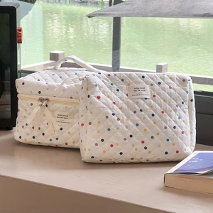 Quilted cotton makeup bag set with colorful polka dots on a window ledge