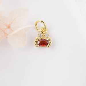 Macro shot of gold-plated crab pendant with oval red gemstone and zircon accents