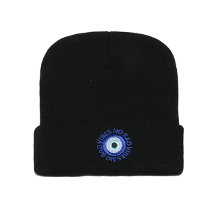 Detail of black knit beanie featuring evil eye embroidery and No Bad Vibes text