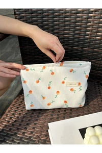Close-up of corduroy makeup bag with orange fruit pattern and a metal zipper detail