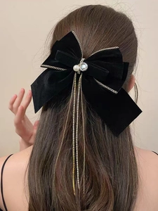 Dettaglio del grande fiocco in velluto nero con perle e nappine in metallo dorato