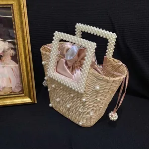 Handwoven straw bucket bag with pearl handles and pink satin drawstring lining