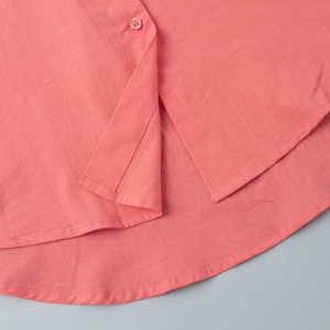 Detail of coral cotton shirt showing hemline curve and high-quality fabric texture