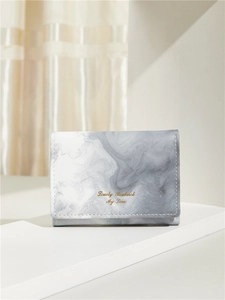 Detail of compact marble texture wallet with gold stamped lettering on geometric stand