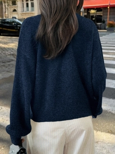 Vue arrière d'un pull en maille bleu marine porté par un mannequin dans une rue urbaine