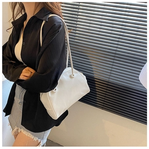 Close-up of a white minimalist shoulder bag with fine faux leather texture and metallic ring