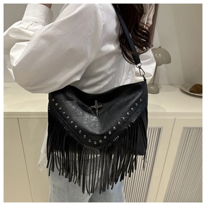 Black leather shoulder bag with silver studs and long fringe shown on a model