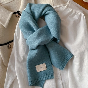 Detail showing foggy blue knitted scarf texture with emo label on beige jacket